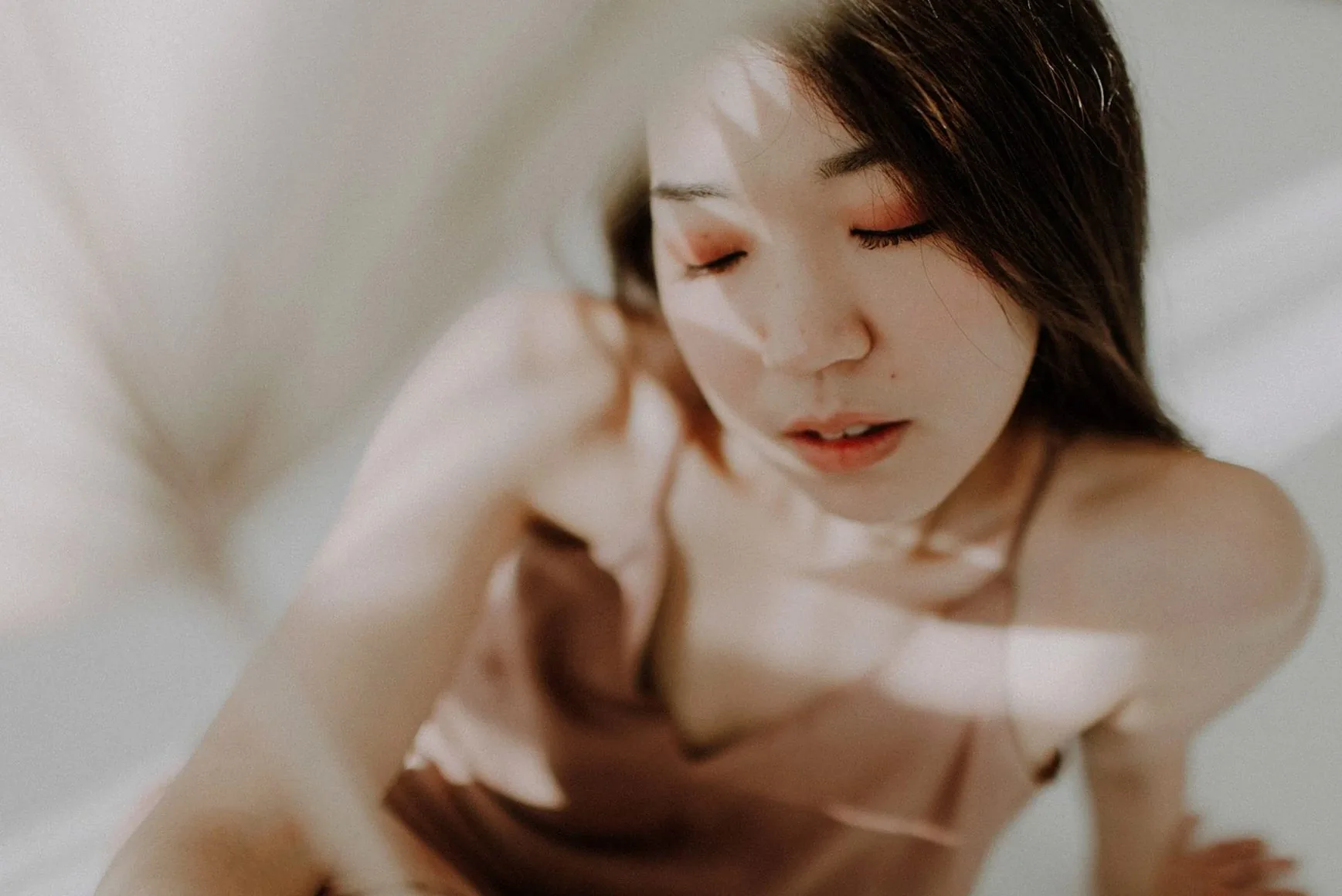 目を閉じて、やわらかな光に包まれる女性のポートレート(イメージ写真)